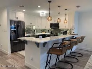 a kitchen with stainless steel appliances kitchen island a table chairs in it and wooden floors