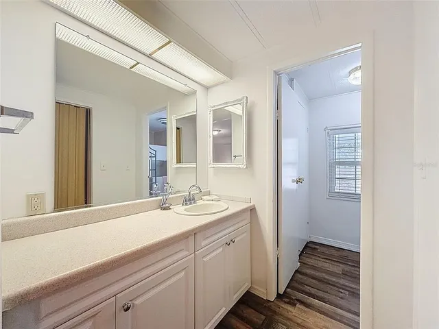 a living room with couches and kitchen view with wooden floor