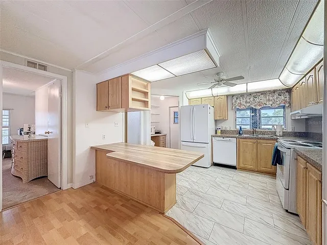 a room with stainless steel appliances kitchen island granite countertop a table chairs and a refrigerator