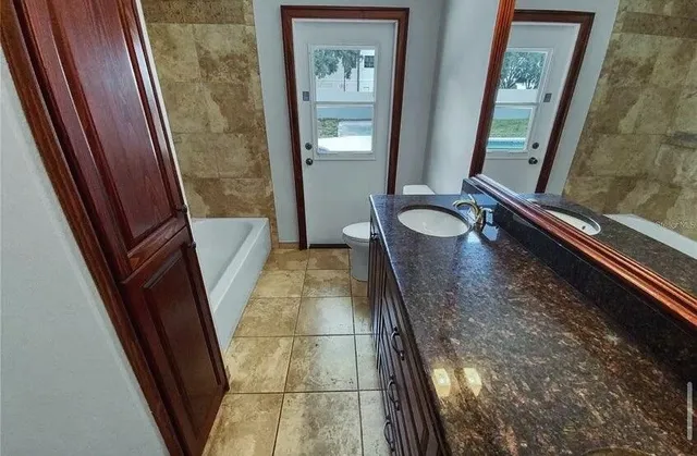 a bathroom with a sink and mirror with bathtub