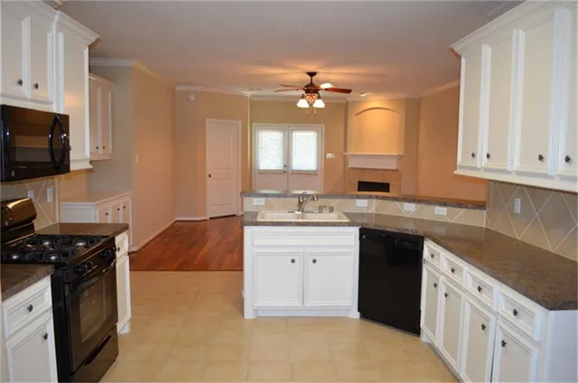 a kitchen with granite countertop a stove a sink dishwasher and a refrigerator with wooden floor