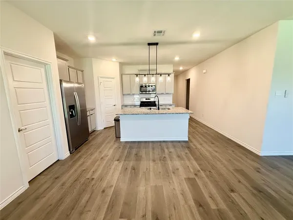 a view of a kitchen with a sink refrigerator and wooden floor