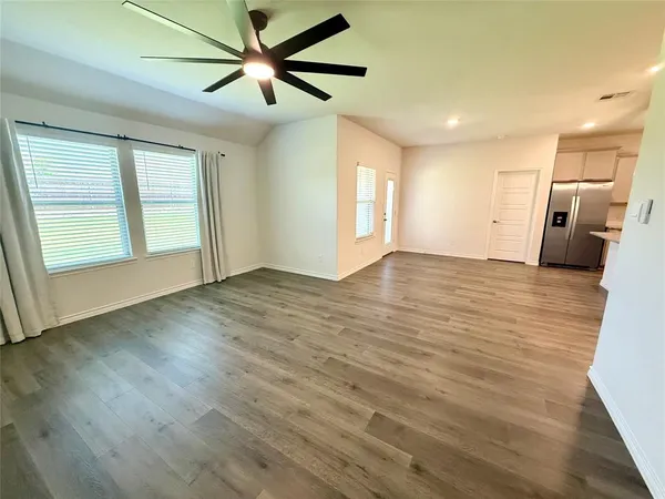 a view of empty room with wooden floor and fan