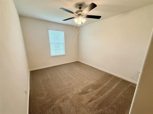 an empty room with a window and a ceiling fan