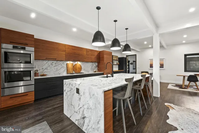 a kitchen with stainless steel appliances kitchen island granite countertop a stove a sink a dining table and chairs with wooden floor