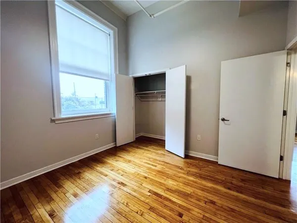 an empty room with wooden floor closet and windows