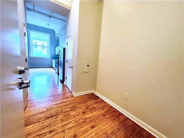 a view of a hallway with wooden floor and a bathroom