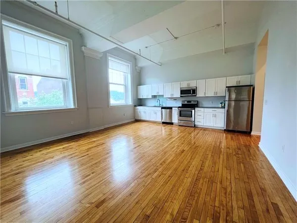 a living room with stainless steel appliances wooden floors and large window