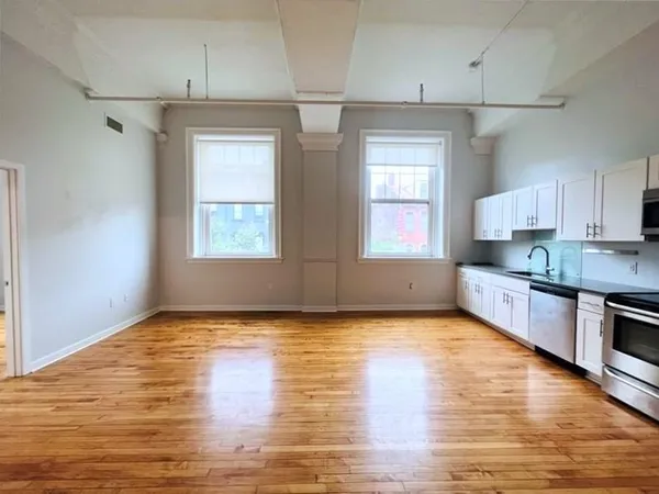 a view of an empty room with window and wooden floor
