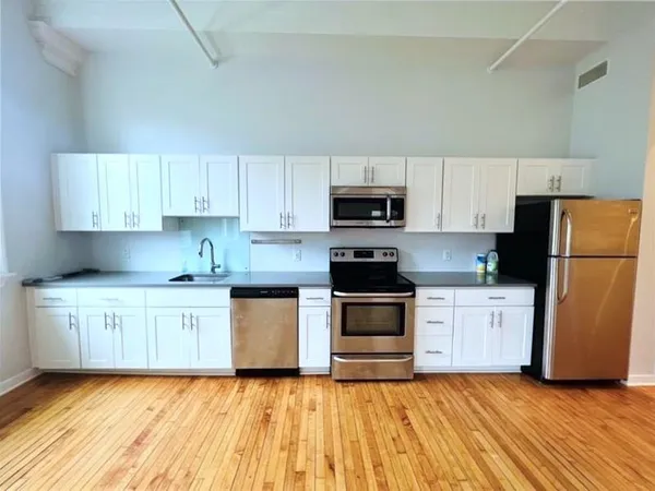 a kitchen with granite countertop a refrigerator a stove top oven a sink and dishwasher with wooden floor