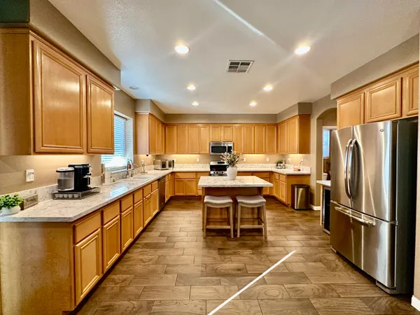 a large kitchen with stainless steel appliances granite countertop a stove a sink dishwasher and a refrigerator with wooden floor
