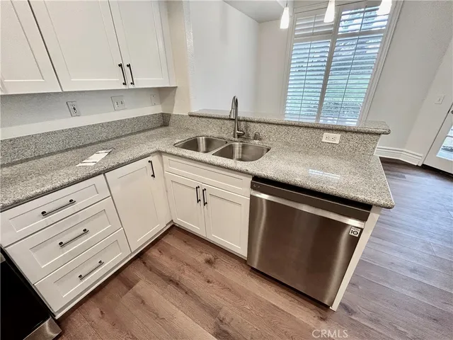 a kitchen with granite countertop white cabinets appliances a sink and a window