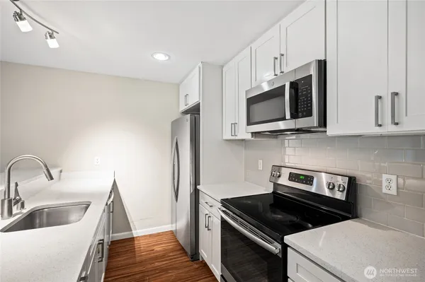 a kitchen with stainless steel appliances a stove a microwave and a sink