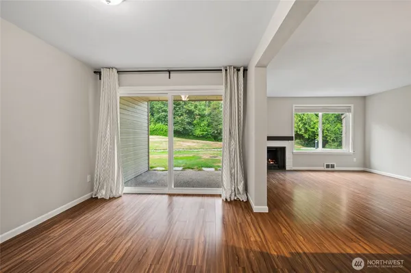 a view of an empty room with wooden floor and a window