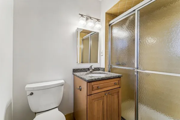 a bathroom with a granite countertop sink a toilet a mirror a bathtub and shower