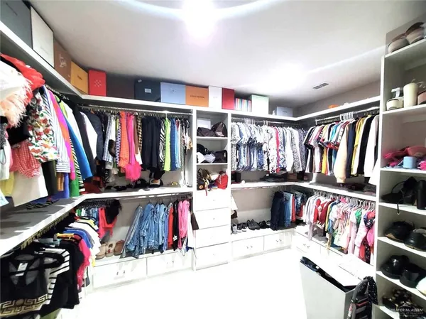 a view of walk in closet with clothes and shoes