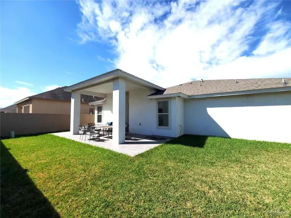 a view of a backyard with table and chairs under an umbrella