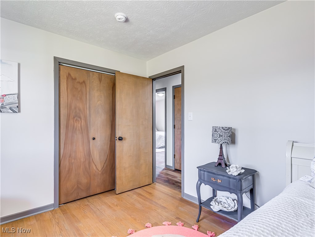 3995 Cottage Grove Road Uniontown, OH 44685 - Photo 24 of 29 Bedroom with a closet, a textured ceiling, baseboards, and light wood-style floors