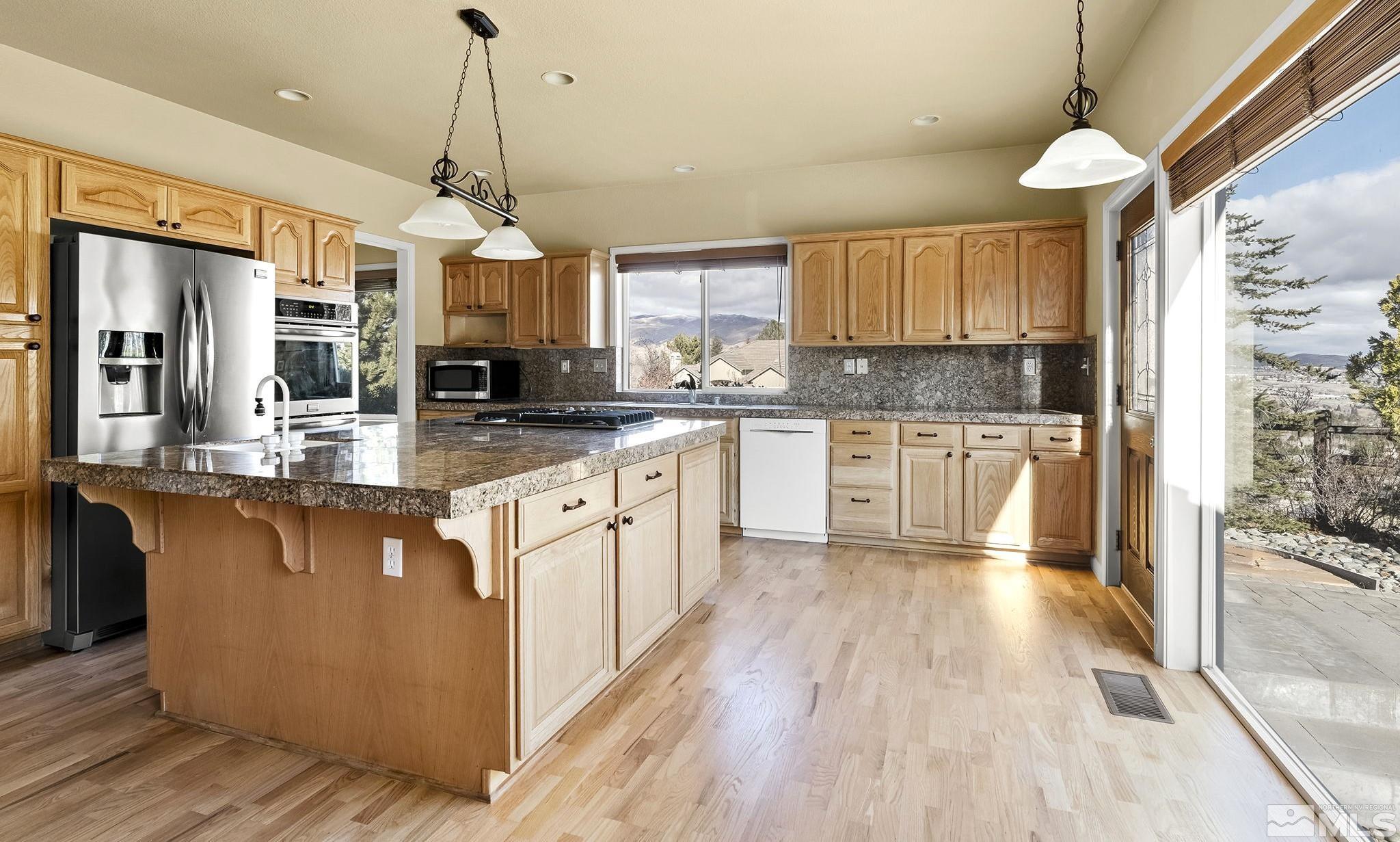 3420 Cheechako Drive Reno, NV 89519 - Photo 5 of 30 a kitchen with stainless steel appliances granite countertop a refrigerator a sink dishwasher a stove and white countertops with wooden floor
