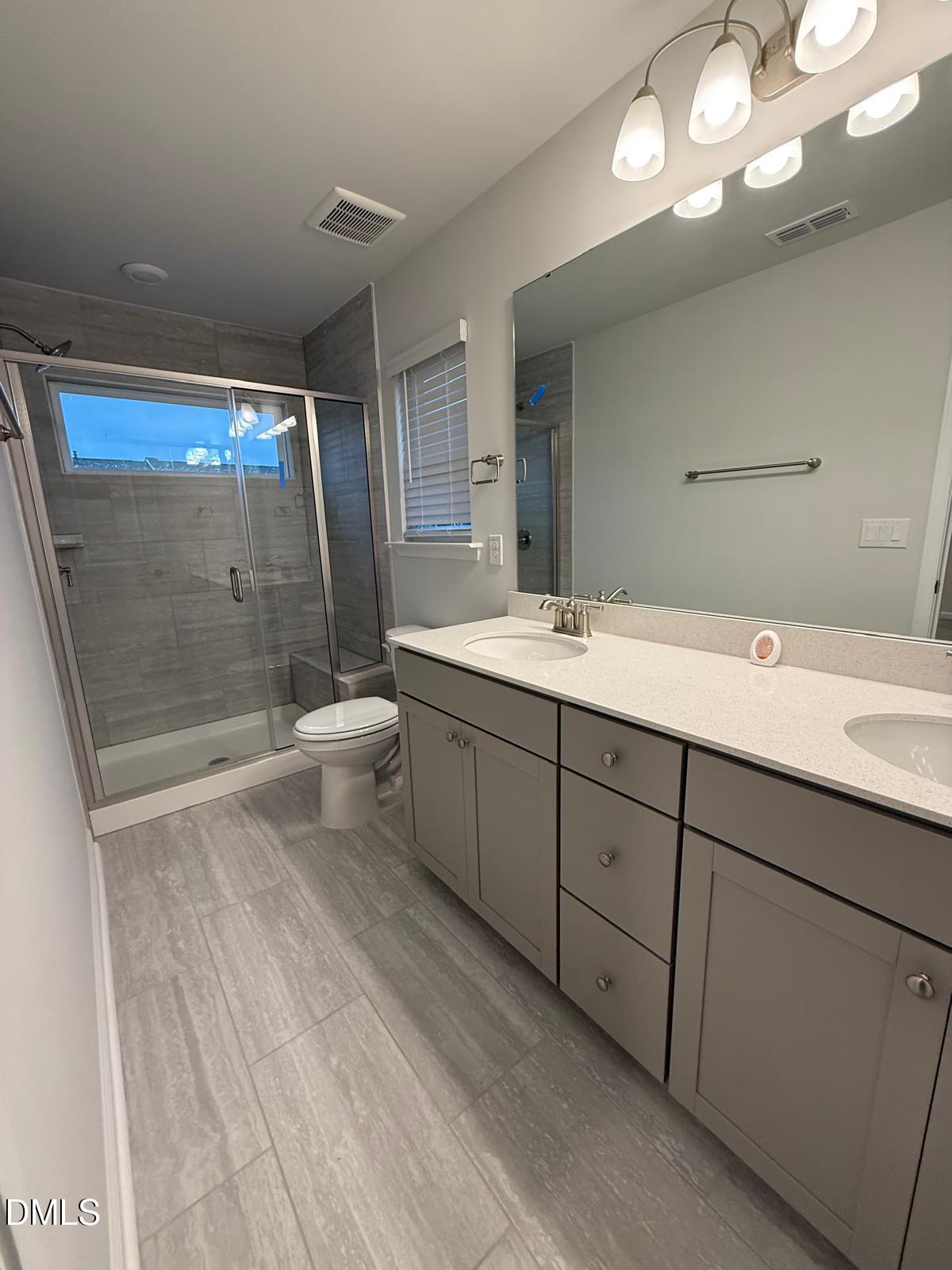 7224 Morris Acres Road Apex, NC 27523 - Photo 14 of 23 a spacious bathroom with a double vanity sink toilet mirror and shower