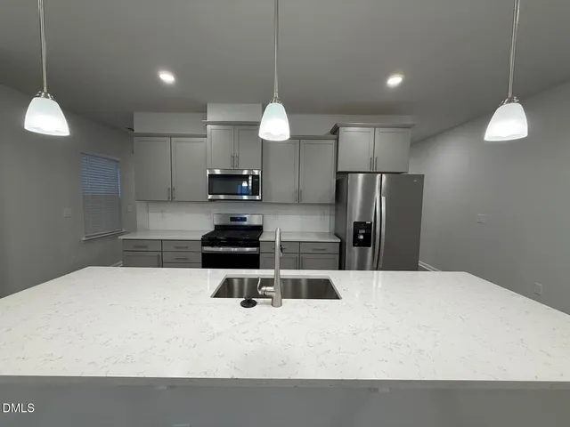 a large kitchen with kitchen island white cabinetry a refrigerator and a stove