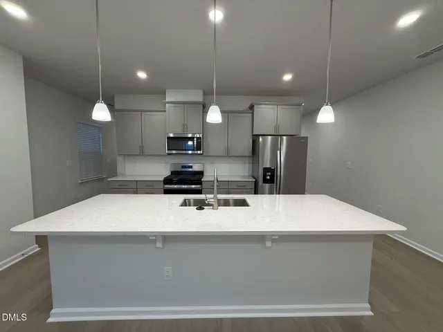 a view of a kitchen with kitchen island a sink stainless steel appliances and a chandelier