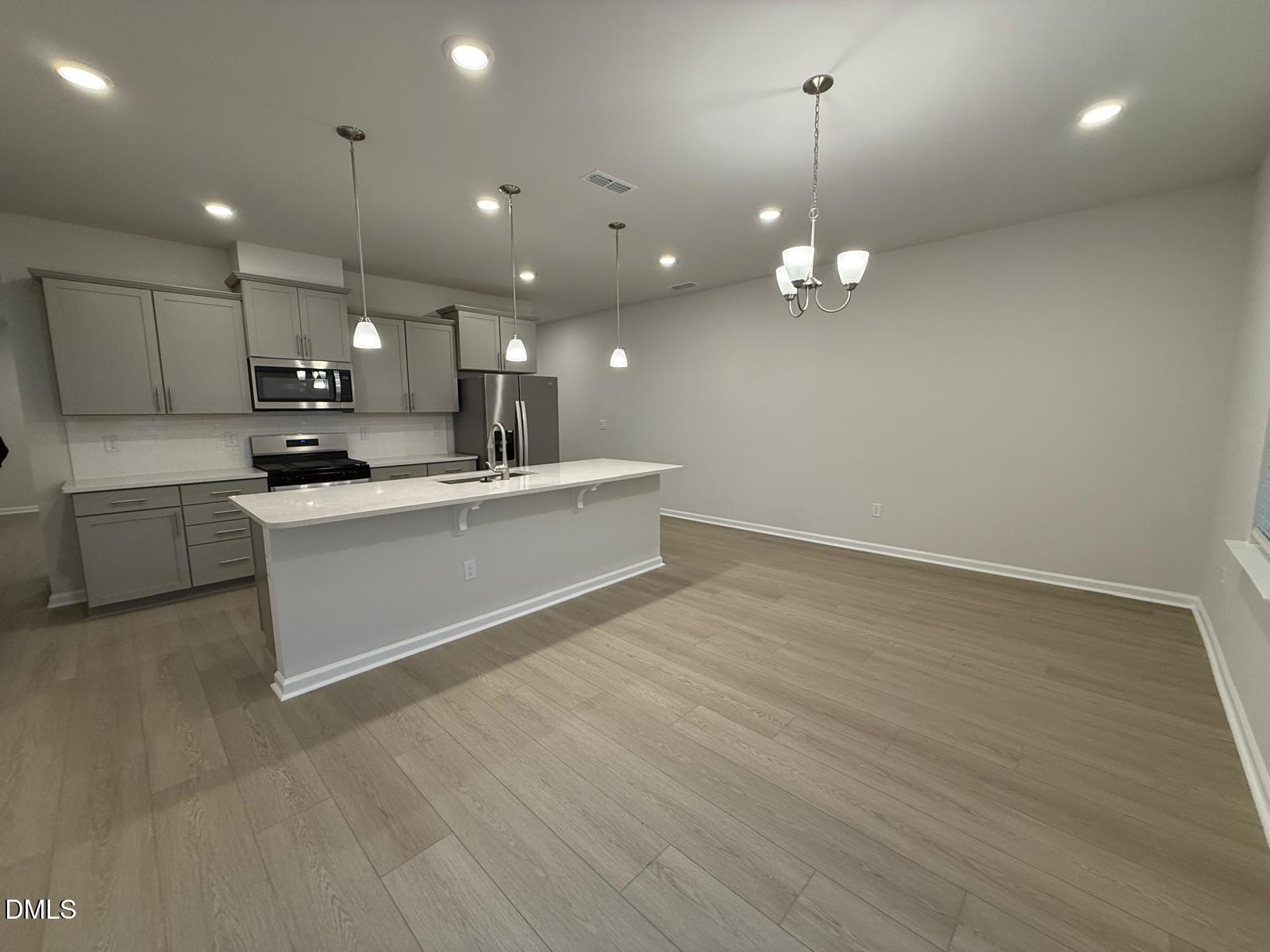 7224 Morris Acres Road Apex, NC 27523 - Photo 6 of 23 a view of a kitchen with kitchen island a sink stainless steel appliances and a chandelier