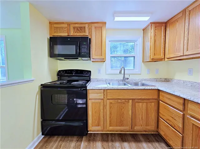 a kitchen with granite countertop a sink stove and cabinets
