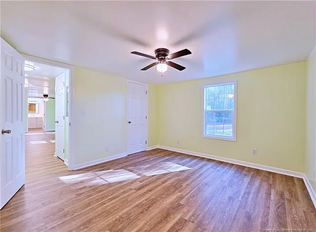 an empty room with wooden floor and windows