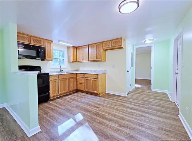 a view of a kitchen with a sink wooden floor and a living room