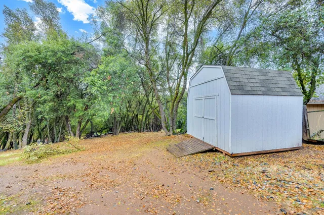 a backyard of a house with large trees and covered with wooden fence