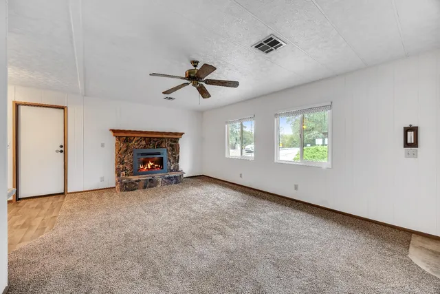 an empty room with windows and ceiling fan
