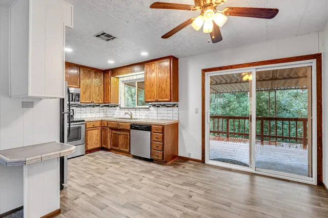 a large kitchen with stainless steel appliances granite countertop a stove a sink dishwasher and a refrigerator with wooden floor