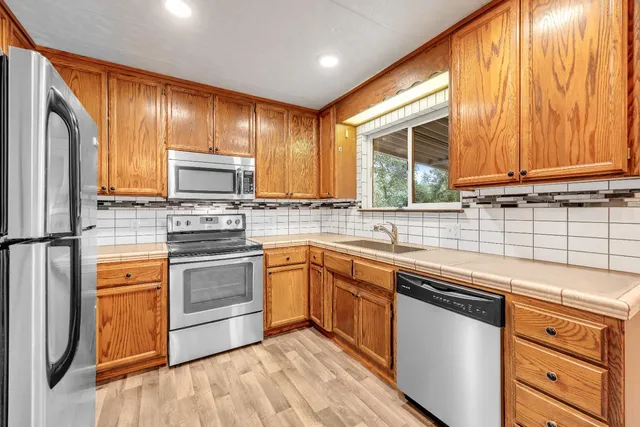 a kitchen with stainless steel appliances granite countertop wooden cabinets a sink and a stove