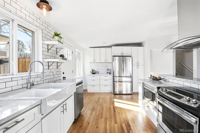 a kitchen with stainless steel appliances kitchen island granite countertop a sink and a white cabinets