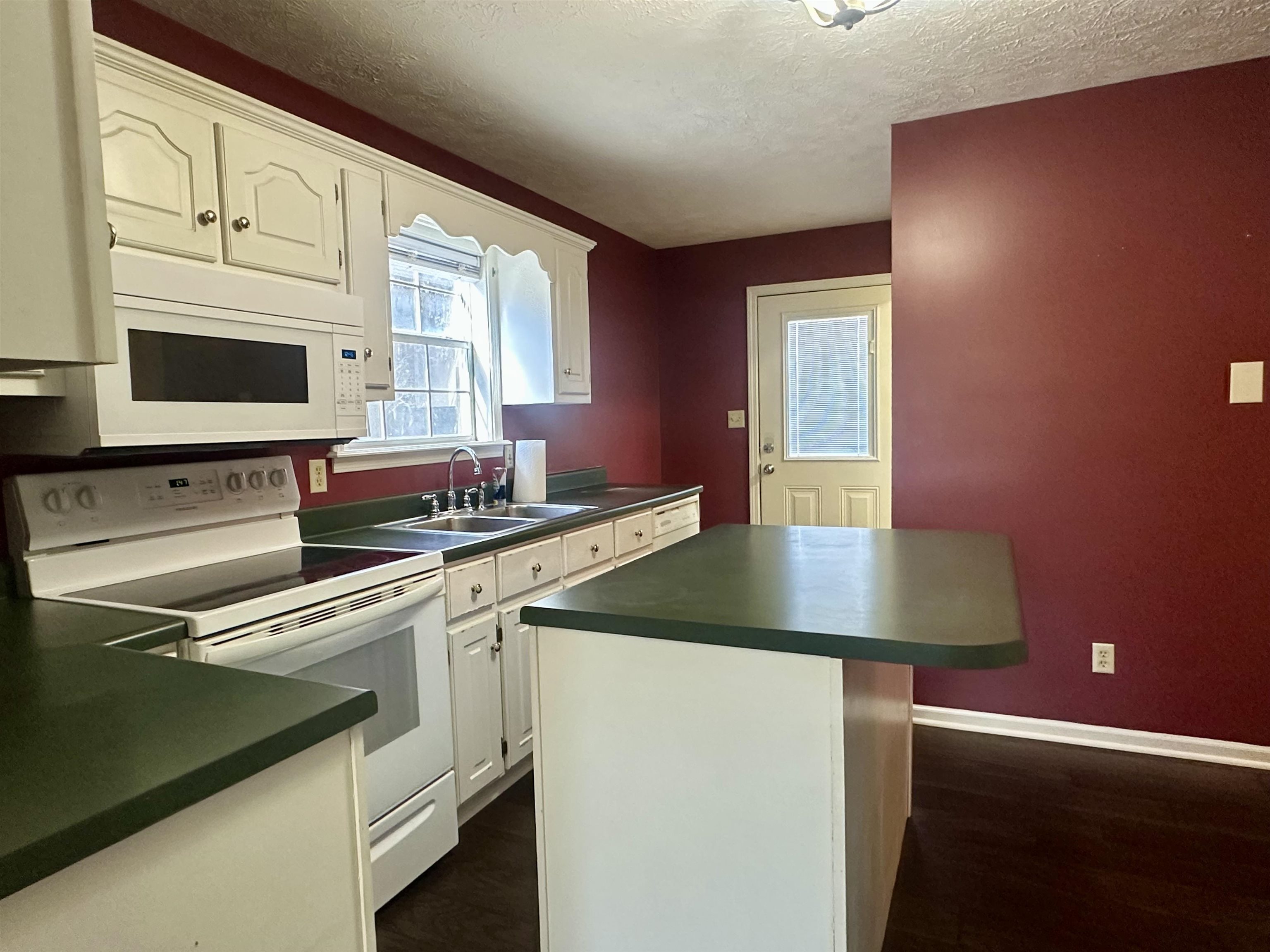 3566 Highway 142 Selmer, TN 38375 - Photo 6 of 20 Kitchen featuring white appliances, dark countertops, white cabinetry, a textured ceiling, and dark wood finished floors