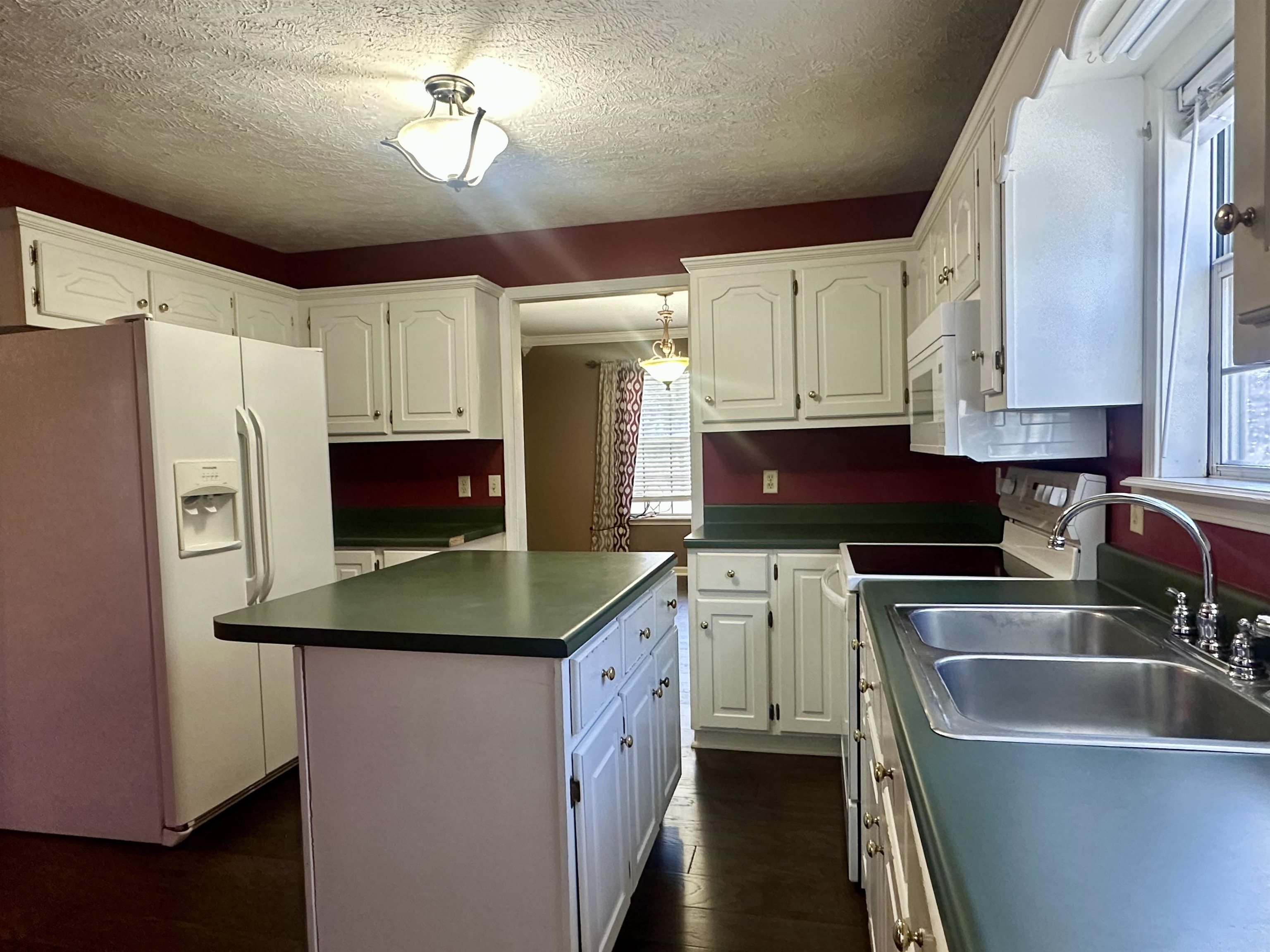3566 Highway 142 Selmer, TN 38375 - Photo 7 of 20 Kitchen with white appliances, a kitchen island, dark wood-style floors, a textured ceiling, and white cabinetry