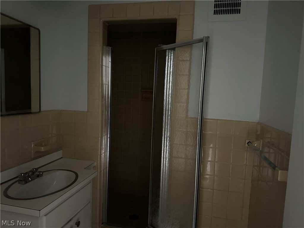 13800 Fairhill Road, Unit 416 Shaker Heights, OH 44120 - Photo 9 of 13 Bathroom featuring a white vanity with an integrated sink and chrome faucet, a rectangular mirror, and beige tiled walls