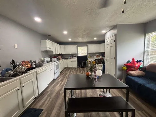 a kitchen with stainless steel appliances a dining table chairs stove refrigerator and cabinets