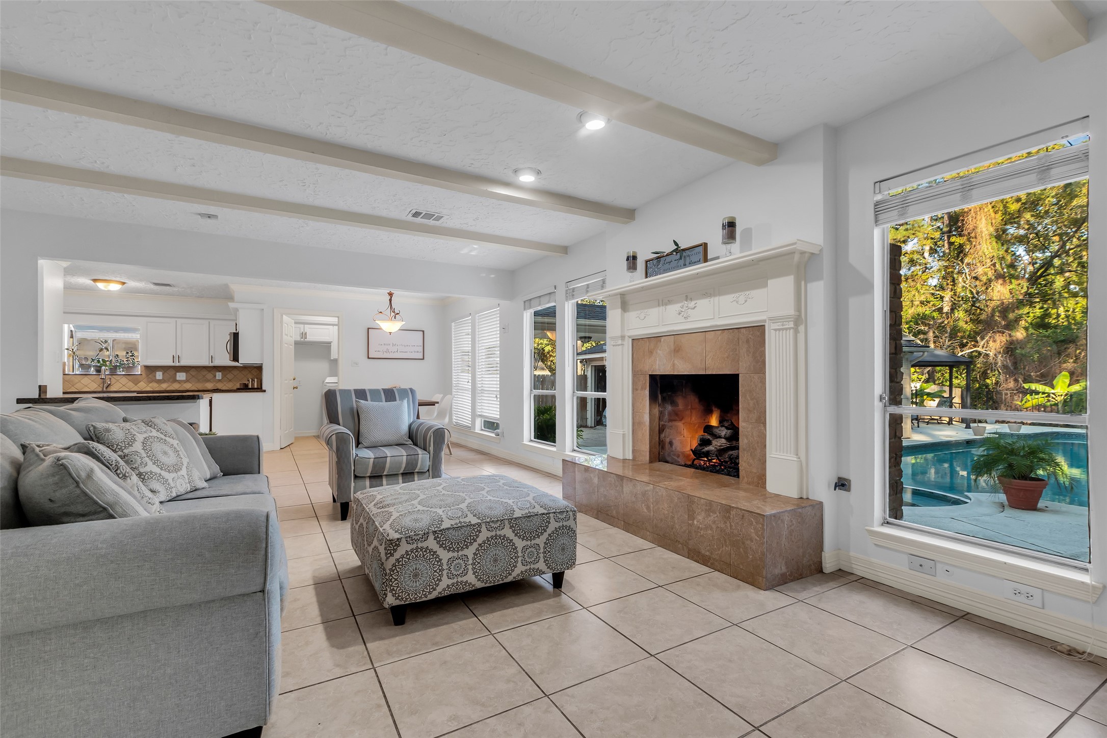 24102 Northcrest Drive Spring, TX 77389 - Photo 6 of 31 Bright and spacious living area featuring a cozy fireplace, large windows with pool views, and a seamless flow into the dining and kitchen spaces. Perfect for relaxation and entertaining.