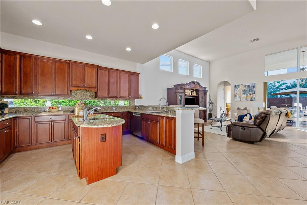 19261 La Serena Drive Estero, FL 33967 - Photo 25 of 48 a kitchen with stainless steel appliances granite countertop a stove a sink dishwasher and a living room with a couch