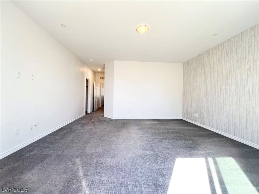 925 Bayberry Ridge Street Henderson, NV 89052 - Photo 13 of 27 A spacious, naturally illuminated room featuring plush carpeting and a striking accent wall.