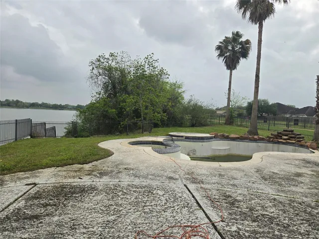 a view of a swimming pool with a yard and palm trees