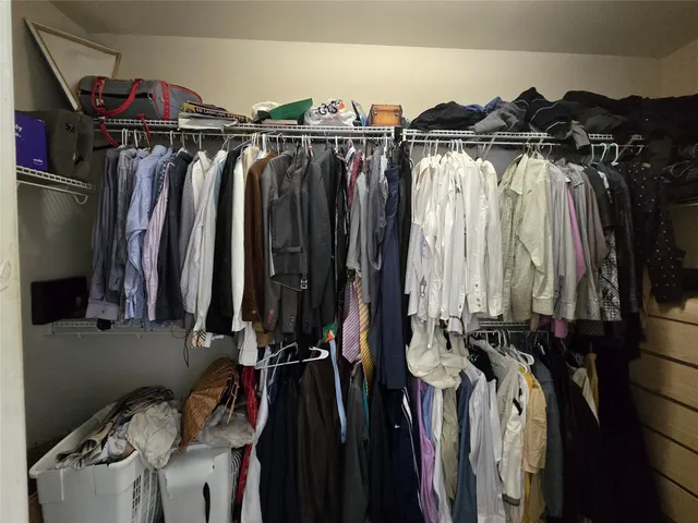 a view of walk in closet with clothes and shoes