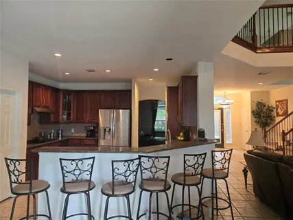 a kitchen with stainless steel appliances granite countertop a stove a sink a refrigerator and chairs