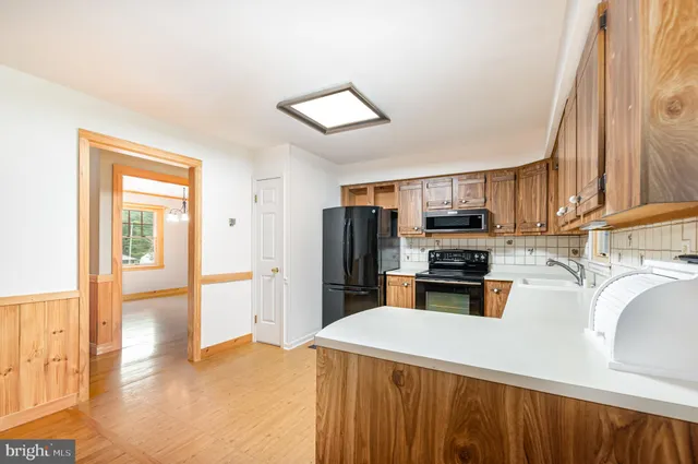 a kitchen with a refrigerator a stove and a sink with wooden floor