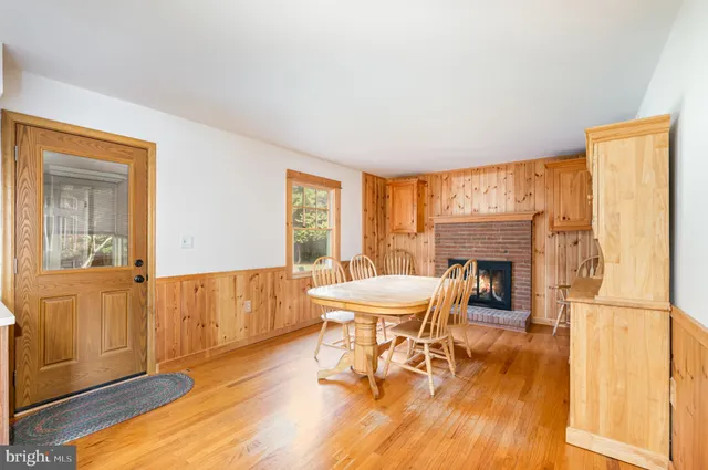 a view of a dining room with furniture a fireplace and wooden floor