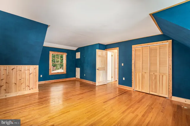 a view of an empty room with window and wooden floor