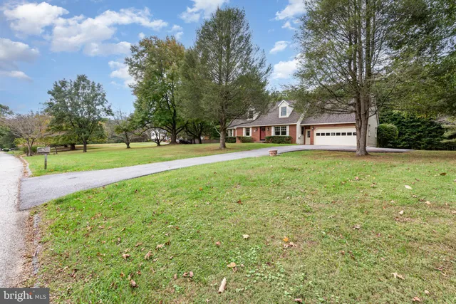 a view of a big house with a big yard and large trees