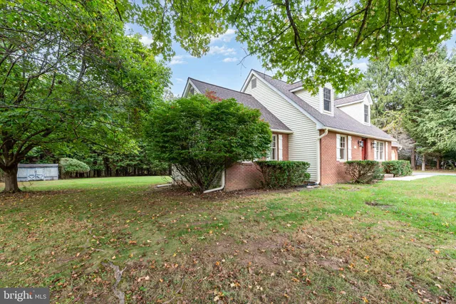 a view of a house with a yard and large trees